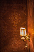 Sconce lamps on wall with Baroque-style wallpaper