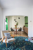 Armchair on patterned rug in front of open doorway leading into dining room