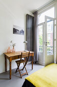 Vases on wooden table and chair next to balcony doors in bedroom