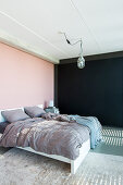 Doppelbett im Schlafzimmer mit rosa und schwarzen Wänden