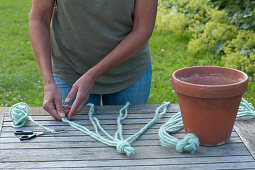 Woman knots blue cords for a macrame hanging basket