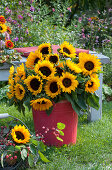 Üppiger Strauß aus Sonnenblumen im roten Blechkübel