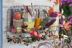 Wall hangers for storing utensils: twine, stick-in labels, small devices and books, ornamental apples and blackberry twig as decoration