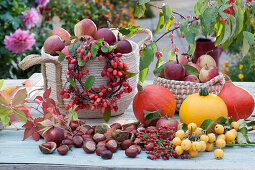 Ornamental wreath on a basket with freshly picked apples, chestnuts, pumpkins and wild wine as decoration