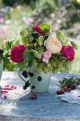 Small autumn bouquet of roses, hops and blackberries in a coffee cup