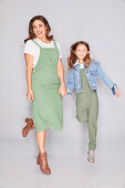 A mother and daughter wearing similar outfits (a green pinafore dress and green dungarees)