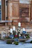 Advent arrangement of white candles on logs with numbered signs