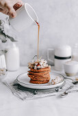 Ahornsirup fließt auf Kürbis-Pancakes garniert mit weißen Johannisbeeren