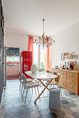 An oval table with chairs and a red refrigerator in a dining room