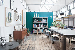 A dining table with classic chairs, a sideboard and an open shelf in a loft apartment