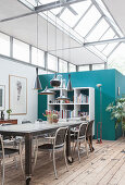 A rollable dining table with chairs and open shelving in a loft apartment