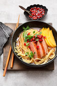 Asian noodle bowl with fried duck breast and mango