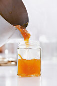 Pouring orange jam into glass jars