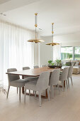 Pale grey upholstered chairs at long dining table in open-plan interior