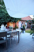 Table and chairs on terrace in courtyard garden at twilight