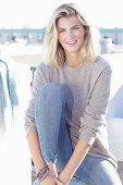 Junge blonde Frau in hellem Pullover und Jeans