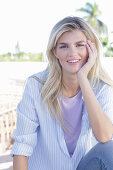 A young blonde woman wearing a purple t-shirt and a blue-and-white striped shirt