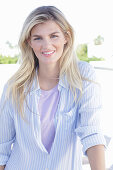 A young blonde woman wearing a purple t-shirt and a blue-and-white striped shirt