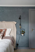 Doppelbett mit Bettwäsche und Tagesdecke in Beige, vor grauer Wand