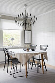 A dining area with various chairs and chandeliers in front of a tiled wall