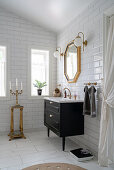 A washbasin and a gold-framed mirror in a bathroom with white subway tiles