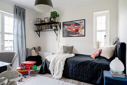 A bed with a dark blanket and toys in a boy's room