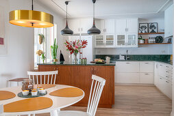An open-plan kitchen with a green marble worktop, a kitchen island and a dining area