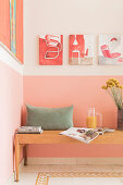 A wooden bench with pillows against a pink wall in a kitchen