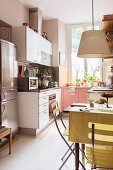 A fridge-freezer in a fitted kitchen with a table and garden chairs in the foreground