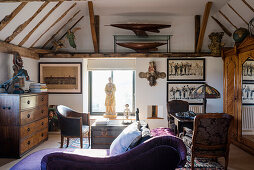 Purple chaise longue with statue in window and writing table lit by an 60’s lamp