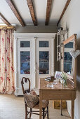 Vitrine, florale Vorhängen und Frisiertisch aus Holz mit Stuhl im restaurierten Bauernhaus