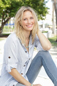 Blonde Frau in hellblau gestreiftem Hemd und Jeans