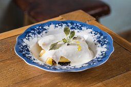 Ravioli garnished with bechamel sauce and sprig of fresh herb