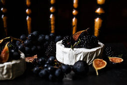 A black counter with brie with concord grapes, figs, blackberries and thyme