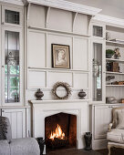 Wohnzimmerwand mit viktorianischer Holzverkleidung und intergriertem Kamin mit Feuer
