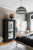 Black wardrobe with mirrored door and old metal twin beds in the guest room