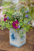 Bouquet of cosmea, lady's mantel, viper's bugloss, allium and poppy seed heads in tin