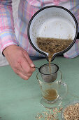 Straining tea from dried parts of plants into a glass