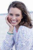A young brunette woman by the sea wearing a knitted jumper