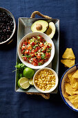 Ingredients for chilaquiles - black beans, tortilla chips, corn and salsa