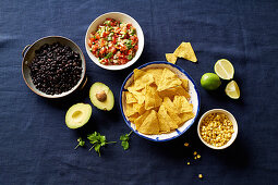 Ingredients for chilaquiles - black beans, tortilla chips, corn and salsa