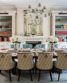 Upholstered chairs with rings on backs around elegantly set table in dining room