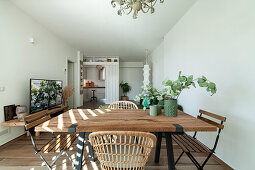 Dining table with various chairs and TV in the background in open-plan living room