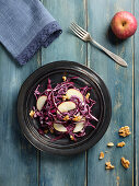 Red cabbage salad with apples wedges and piece of nuts