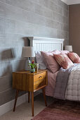 Retro bedside cabinet in feminine bedroom in pastel shades