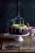 Schokoladen-Gugelhupf mit Pistazienglasur und vier ausgepusteten Kerzen
