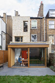 Woman sitting at dining table in modern extension of brick house