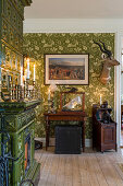 Tiled stove and antiques in room with green wallpaper