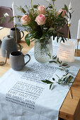 Bouquet of roses on set table; table runner with writing motif