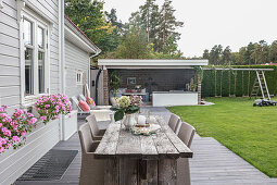 Rustikaler Holztisch mit eleganten Rattanstühlen auf der Terrasse